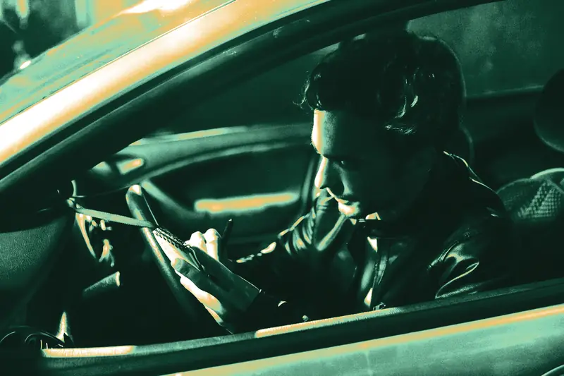 Driver sitting in a parked car at night, writing notes in a small notebook